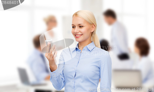 Image of young smiling businesswoman with smartphone