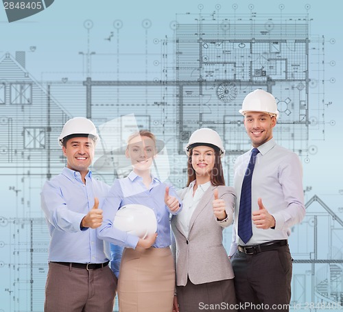 Image of happy business team in office showing thumbs up