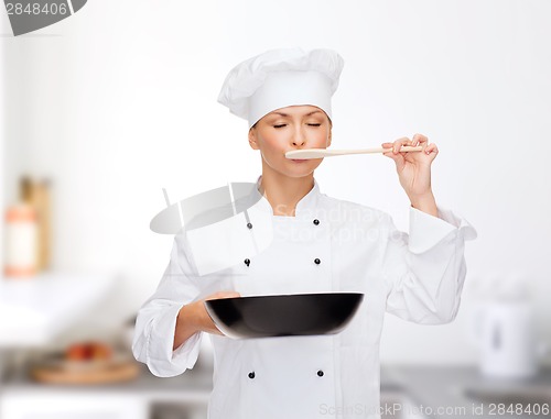 Image of smiling female chef with pan and spoon