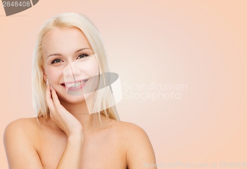 Image of smiling young woman touching her face skin