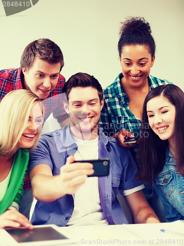 Image of students looking into smartphone at school