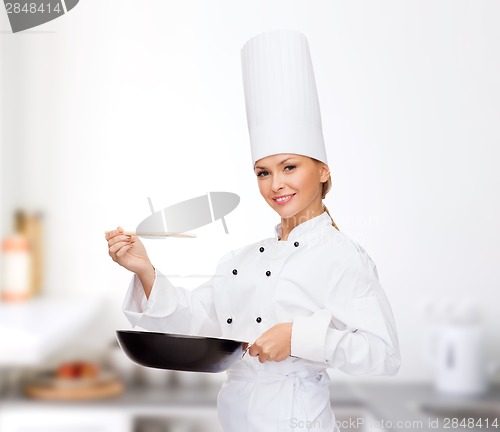 Image of smiling female chef with pan and spoon