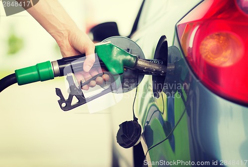 Image of man pumping gasoline fuel in car at gas station