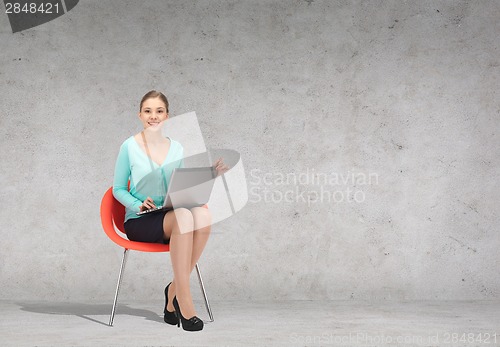 Image of young businesswoman sitting in chair with laptop