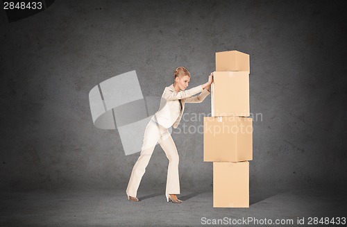 Image of businesswoman pushing tower of cardboard boxes