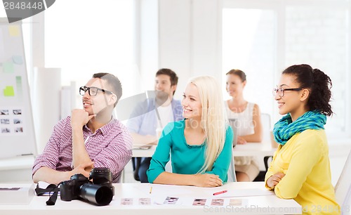 Image of smiling team with photocamera working in office