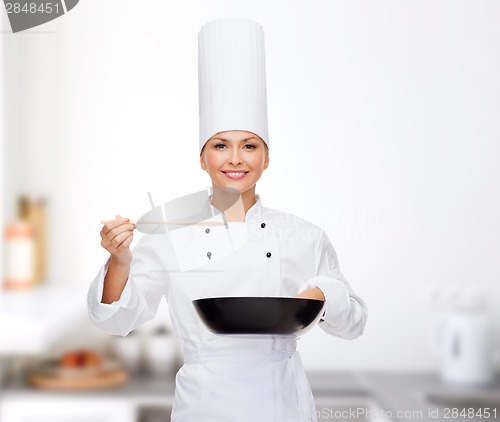 Image of smiling female chef with pan and spoon