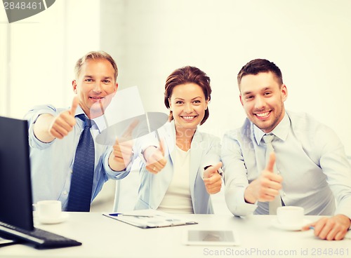 Image of business team showing thumbs up in office