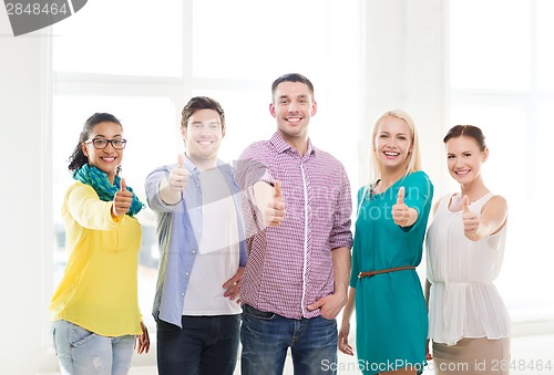 Image of happy creative team showing thumbs up in office