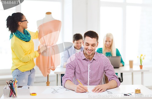 Image of smiling fashion designers working in office