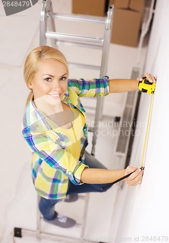 Image of smiling woman measuring wall