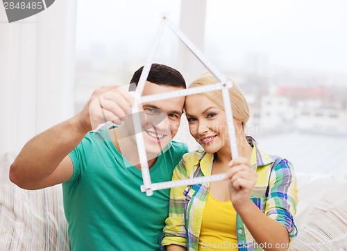 Image of smiling couple with house from measuring tape