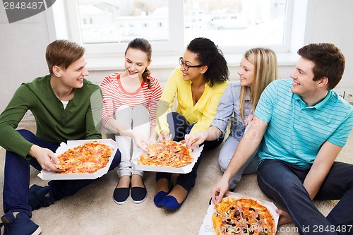 Image of five smiling teenagers eating pizza at home