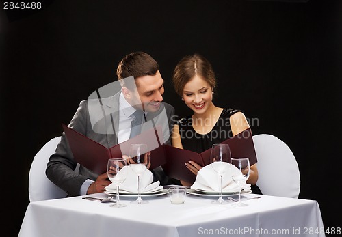 Image of smiling couple with menus at restaurant