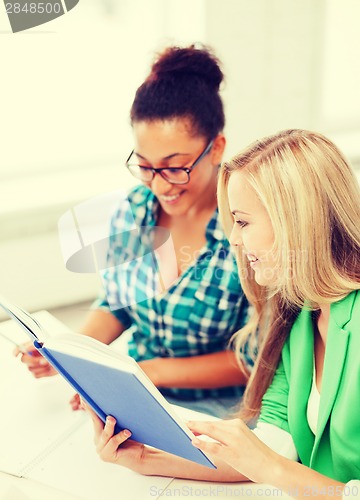 Image of smiling student girls reading book at school