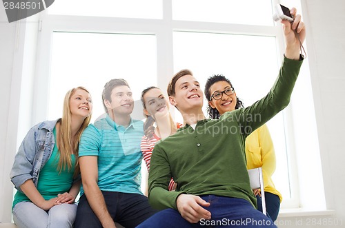 Image of five smiling students taking picture with camera