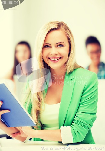 Image of smiling young girl reading book at school
