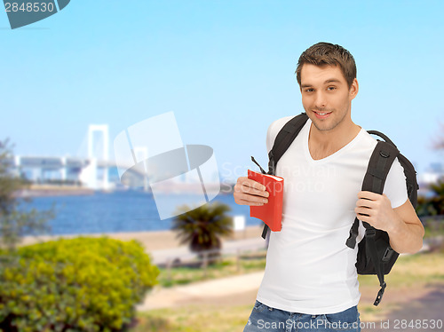 Image of travelling student with backpack and book