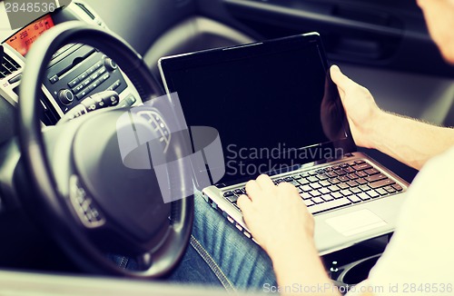 Image of man using laptop computer in car