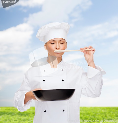 Image of smiling female chef with pan and spoon