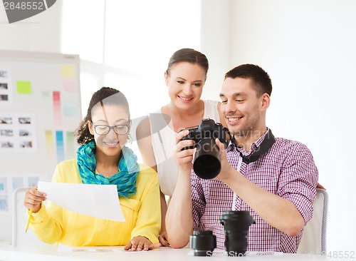 Image of smiling team with photocamera working in office