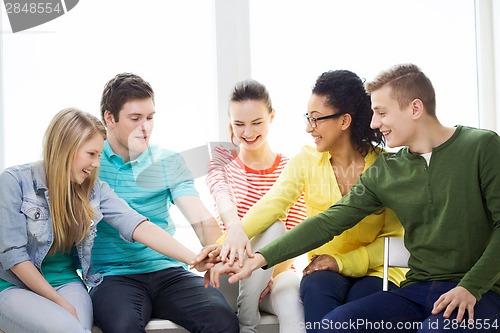 Image of smiling students with hands on top of each other