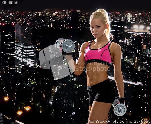 Image of sporty woman with heavy steel dumbbells