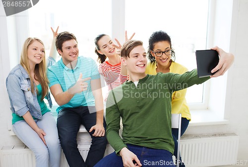 Image of smiling students making picture with tablet pc