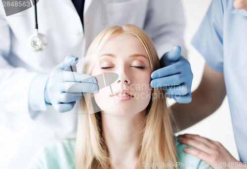 Image of plastic surgeon and nurse with patient