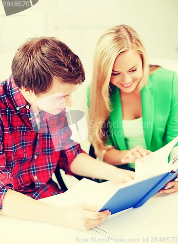 Image of smiling students reading book at school