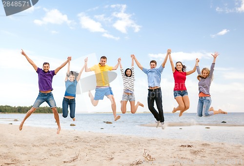 Image of group of friends jumping on the beach