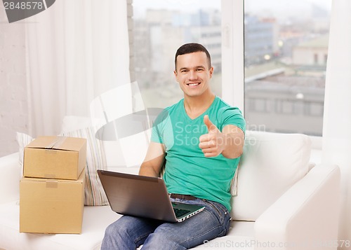 Image of man with laptop and cardboard boxes at home