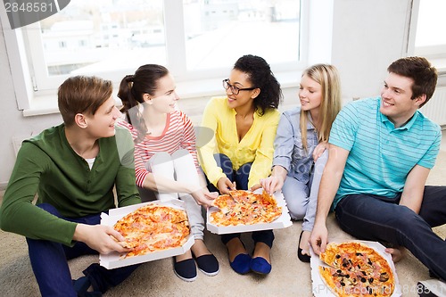 Image of five smiling teenagers eating pizza at home