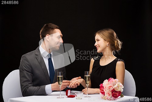 Image of man proposing to his girlfriend at restaurant