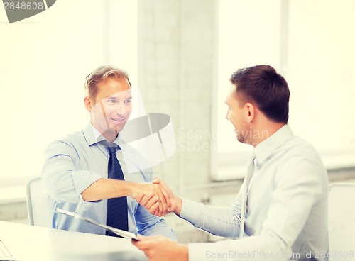 Image of businessmen shaking hands in office