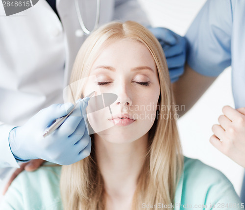 Image of plastic surgeon and nurse with patient