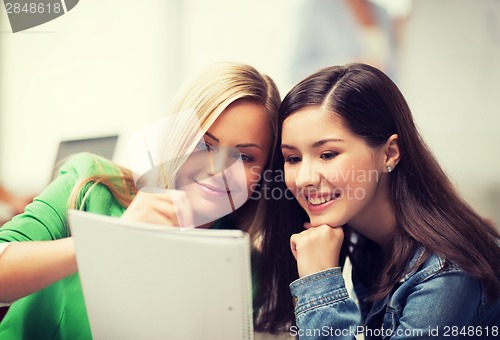 Image of student girls pointing at notebook at school