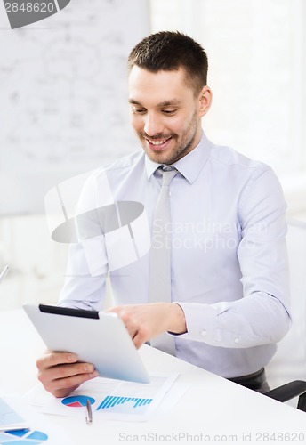 Image of businessman with tablet pc and files in office