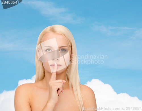 Image of calm young woman with finger on lips