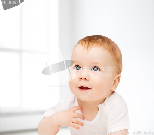 Image of smiling baby lying on floor and looking up