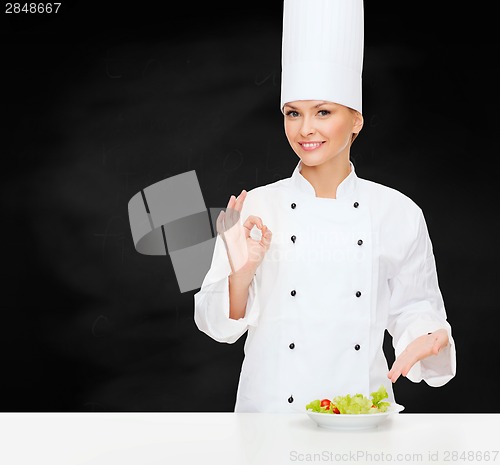Image of smiling female chef with salad on plate