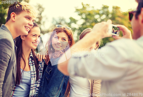 Image of teenagers taking photo with digital camera outside