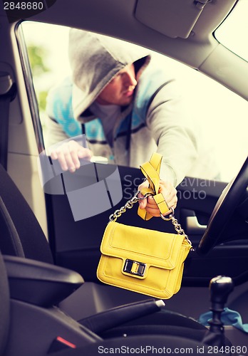 Image of thief stealing bag from the car