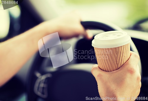 Image of man drinking coffee while driving the car