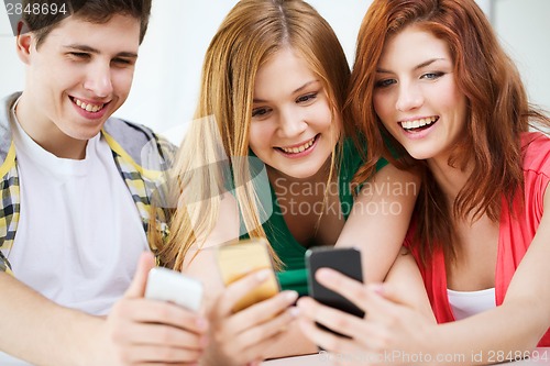 Image of three smiling students with smartphone at school