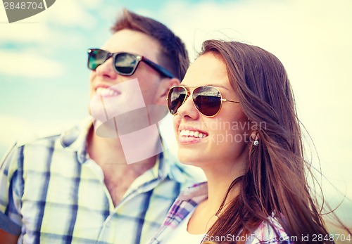 Image of smiling teenagers in sunglasses having fun outside