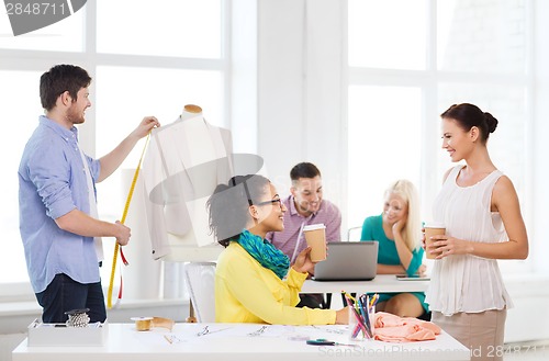 Image of smiling fashion designers working in office