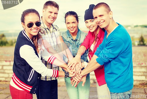 Image of teenagers hands on top of each other outdoors
