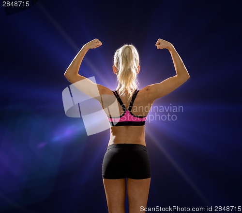 Image of sporty woman from the back flexing her biceps