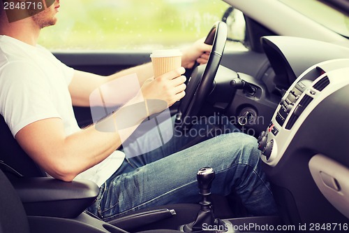 Image of man drinking coffee while driving the car